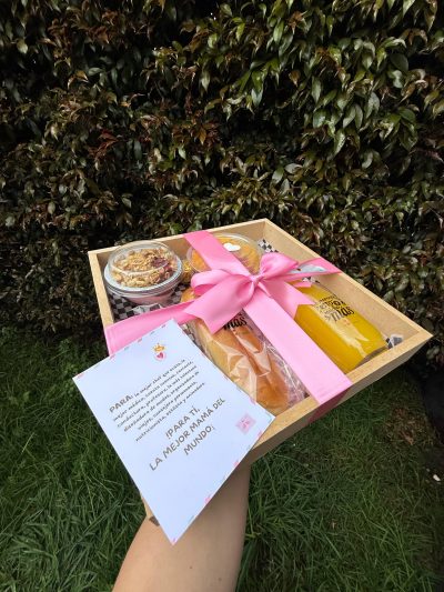 MAMÁ INCOMPARABLE Contiene  -Sándwich de jamón y queso  -Chocolatina   -Jugo de naranja  -Frasquito con yogurt y cereal  -Fruta picada  -Set de cubiertos en madera  -Bandeja en madera-tarjeta predeterminada